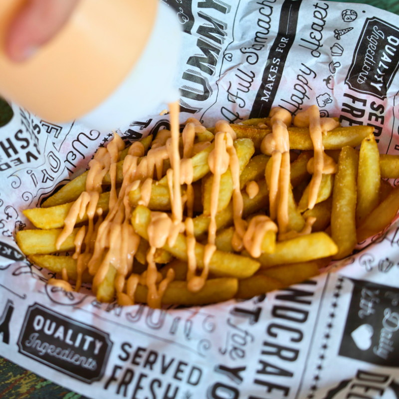 french fries being covered in sauce food photo taken by phoodie media